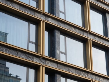 Close-up of premium stone facade and golden window frames of a modern luxury apartment building, soft natural light, 35mm architectural photography