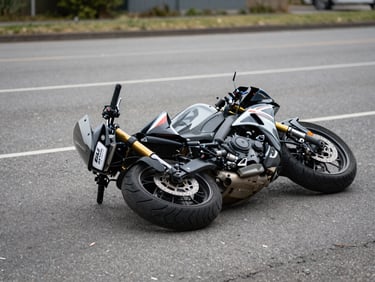 Close documentary frame of a motorcycle lying on its side on asphalt after an impact, natural overcast daylight, no people, case-evidence style photography