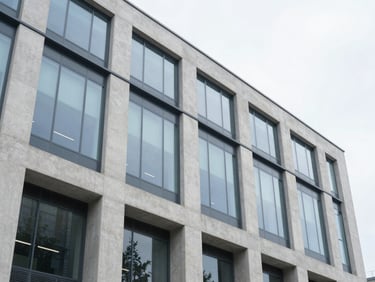 Wide-angle architectural shot of a modern minimalist corporate building facade, concrete and glass, bright overcast daylight, sharp focus, 35mm