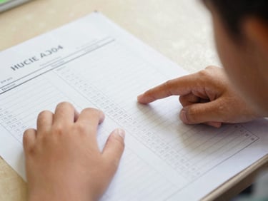 A close-up of a child's hands pointing to high grades on a structured school report card in Indonesian, warm natural daylight, shallow depth of field, authentic documentary style, 35mm