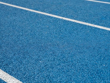High-durability blue polyurethane athletic running track surface, close-up showing technical texture, even studio lighting