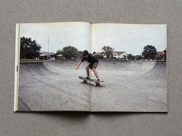 Archival scan of a Belgian skate zine from the 90s, open on a concrete surface, desaturated tones, 35mm skate photography.