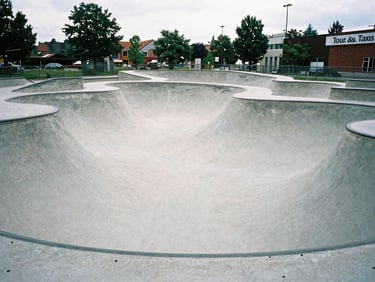 Panoramic view of the renovated concrete skatepark at Tour & Taxis in Brussels, wide shot, overcast daylight, gritty film photography