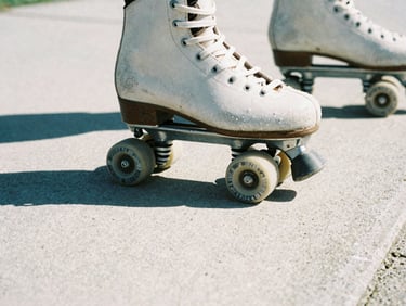 Close-up of worn roller skate wheels grinding on a concrete ledge, harsh direct sunlight casting deep shadows, gritty film photography