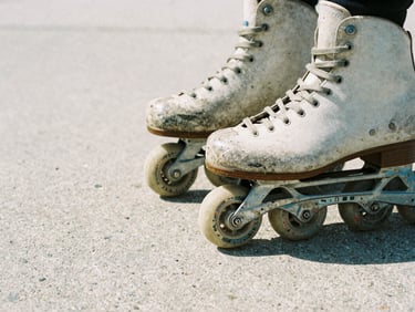 Close-up of vintage inline skates from the 90s, worn wheels, grind plates, on raw concrete, harsh direct sunlight, gritty film photography.