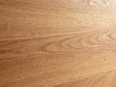 Close-up of premium Indonesian teak wood grain, matte finish, soft side lighting, warm golden tones.