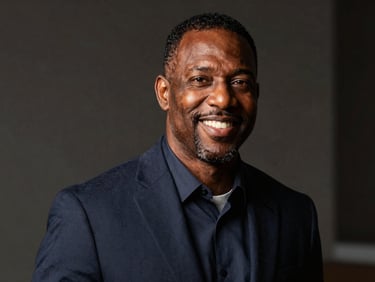 A professional portrait of Michael Harris, a Black male leader in his 40s, focused and smiling warmly, dramatic natural light