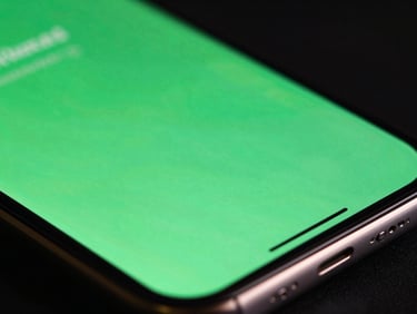 Extreme macro close-up of a high-resolution mobile OLED screen showing fluid neon green UI transitions, low-key dramatic studio lighting with ambient screen glow reflecting off metallic edges, 35mm