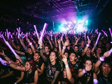 Low angle shot of dynamic crowd with neon purple light sticks raised, high-contrast, energetic concert atmosphere, vibrant cyberpunk event photography, 35mm