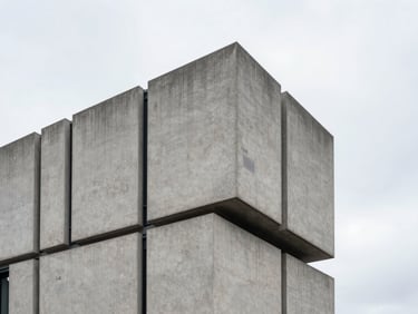 Stark minimalist geometric concrete building in London against overcast sky.
