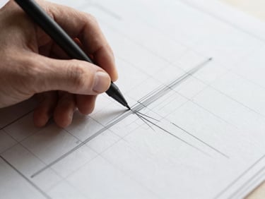 Close-up of hands sketching a technical grid on physical blueprint paper with a drafting pen.