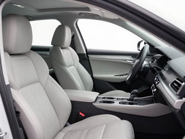 A pristine clean car interior with detailed leather seats and dashboard under bright white utility lighting, looking brand new.