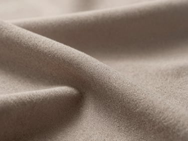 Macro close-up of soft taupe long-staple cotton textile weave, soft diffused side daylight, architectural shadows.