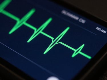 Close-up of a mobile screen showing an active biometric pulse wave graph in bright green on a deep slate canvas, tech studio lighting
