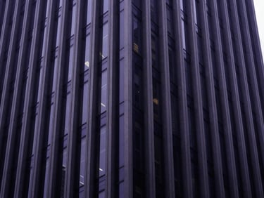 Wide architectural shot of a modern corporate skyscraper facade with clean geometric lines, diffused natural daylight, high contrast, deep navy tones, 35mm premium editorial photography