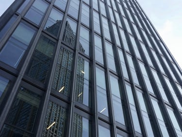 Wide-angle perspective of a modern skyscraper facade with geometric glass panels reflecting daylight