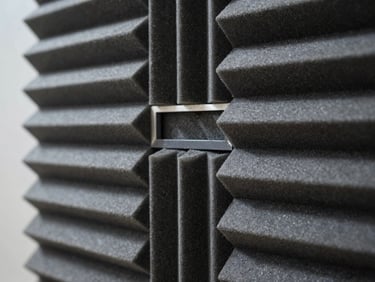 Close-up architectural detail of acoustic panel array mounted on wall, showing precise material joints and absorption surface texture under cool north-facing studio light, shallow depth of field on panel weave pattern.