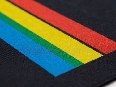 Sharp macro shot of a vibrant multi-color graphic transferred onto black cotton fabric using textile DTF, showing weave texture