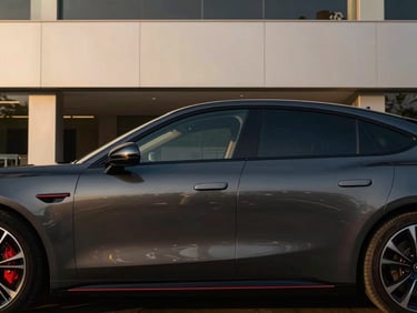 Side profile of a dark graphite luxury sedan, sleek lines, modern architectural showroom background, golden hour lighting.