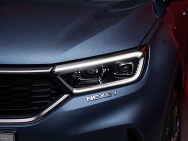 Tight macro detail of a blue Tata Nexon EV headlight and badge, sharp reflections, low-key studio lighting, 35mm prime lens.