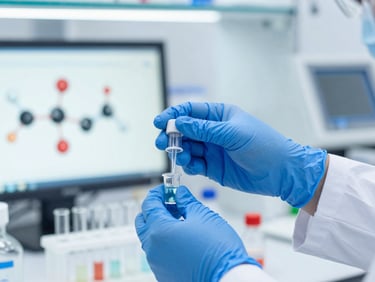 Close-up of a scientist's hands in blue gloves, carefully pipetting solutions into vials in a brightly lit, sterile laboratory environment, molecular models on screen in background, sharp focus.