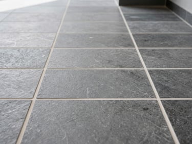 Perfect grid of grey slate floor tiles with crisp white grout lines in a brightly lit entryway, showcasing level alignment.