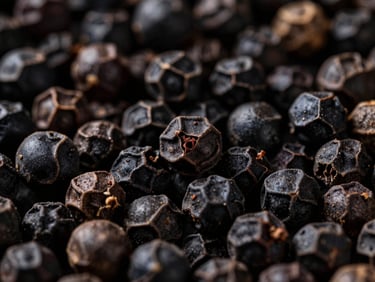Macro close-up of whole Tellicherry black peppercorns, dramatically side-lit, rich deep tones, 35mm, elegant luxury aesthetic, showing texture and sheen.
