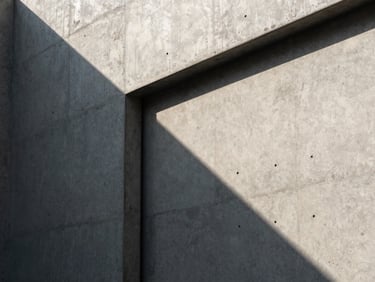 Crisp architectural close-up of a modern concrete wall with sharp geometric shadows, emphasizing raw structural lines under hard afternoon light.
