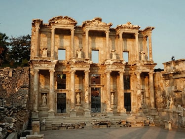Wide environmental shot of ancient Ephesus library ruins at sunrise, no crowds, warm golden light, cinematic 35mm composition.