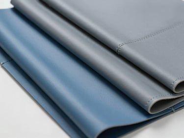 Straight-on catalog shot of hospital upholstery material — close-up of durable vinyl healthcare fabric swatches in clinical blue and gray tones laid flat on a white surface, studio strobe lighting, texture and seam detail clearly visible