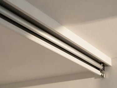 Close-up of a modern white ceiling-mounted sliding curtain track system with metal rollers.