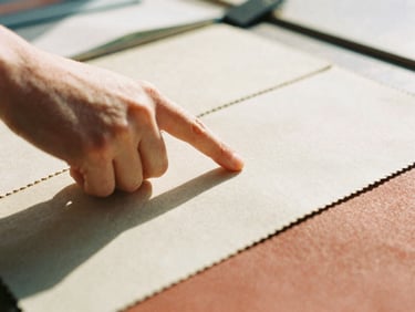 Close-up of a hand pointing to a detail on a technical fabric swatch during a supplier vetting meeting, warm natural daylight, shallow depth of field, 35mm film aesthetic.