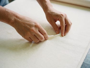 Hands inspecting a sample product (e.g., fabric roll or small component) on a factory floor, focused on texture and quality, soft shadows, 35mm film aesthetic.
