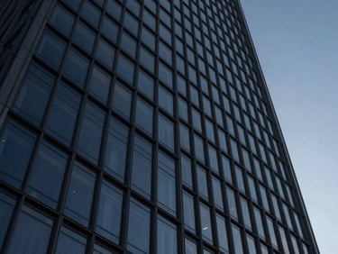 Abstract architectural geometry of a modern steel and glass skyscraper looking up, cool low-key twilight lighting, deep navy and slate tones, sharp focus, 35mm