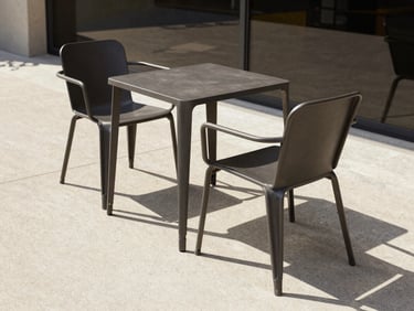 Minimalist outdoor metal furniture set on a commercial terrace, dark charcoal steel chairs with clean geometric lines, sharp shadows, luxury hospitality setting