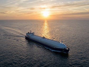 Cinematic wide-angle drone shot of a modern clean product tanker sailing steadily across calm waters during a spectacular golden sunset, warm light reflecting off the sea.