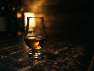 Moody low-key photography of a Glencairn glass with amber whisky on a dark textured wooden table, warm golden backlighting, shallow depth of field, 35mm