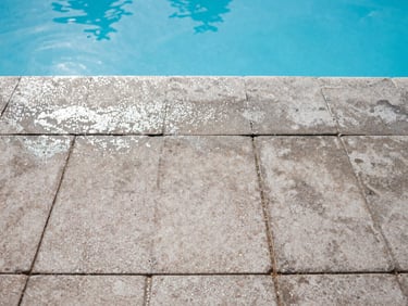 Clean pool deck with water beading on freshly cleaned pavers, bright Florida sunlight, crisp shadows, clear blue sky, 35mm