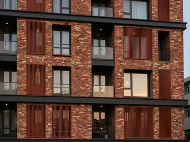 Exterior facade of a premium apartment complex in Guwahati, highlighting modern architectural brickwork and terracotta screens at twilight.