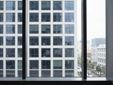 High-end corporate workspace with architectural lines of a modern real estate office building visible through a large window, cool natural light, 35mm.