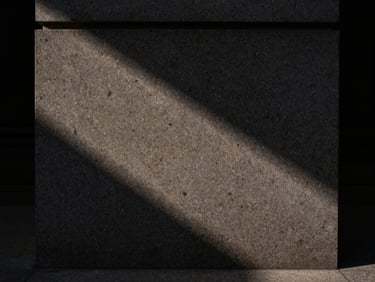 Straight-on architectural detail of honed Belgian bluestone meeting fumed oak, casting dramatic low-key shadows, moody natural side-light, Hasselblad photography.