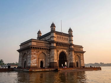 Dynamic low-angle shot of the Gateway of India in Mumbai at sunrise, glowing orange light reflecting on calm waters.