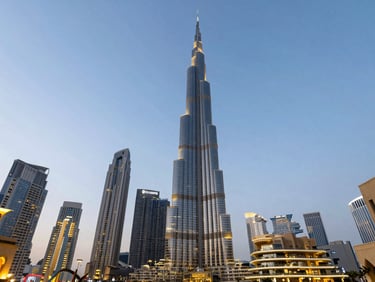 Wide environmental shot of the Dubai skyline with the Burj Khalifa towering into a clear dusk sky, warm architectural lighting.