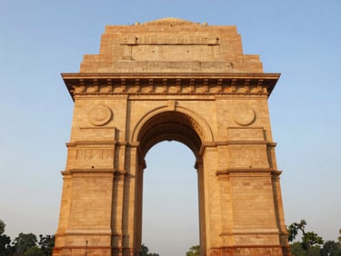 Symmetrical architectural perspective of India Gate in New Delhi under warm golden hour light, clear sky, high-contrast premium photography.