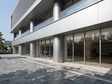 Wide architectural shot of a completed modern commercial interior, bright natural daylight, crisp shadows, slate and metallic tones.