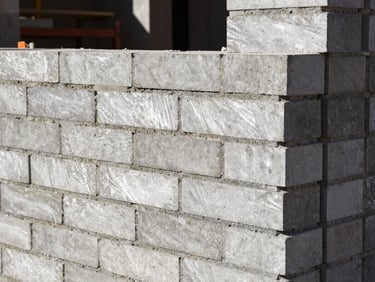 Tight shot of heavy masonry work in progress, clean brick alignments, high-contrast natural site light, sharp focus, 35mm