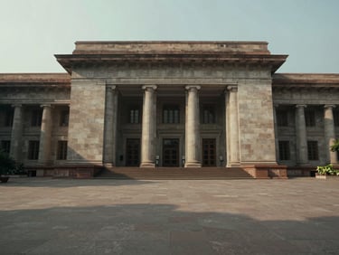 Wide environmental shot of classical New Delhi institutional stone building with geometric shadows, soft diffused daylight, emphasizing symmetry and architectural scale.