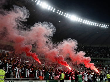 Passionate supporters in the stands of São Januário stadium, red flare smoke, intense matchday atmosphere, 35mm