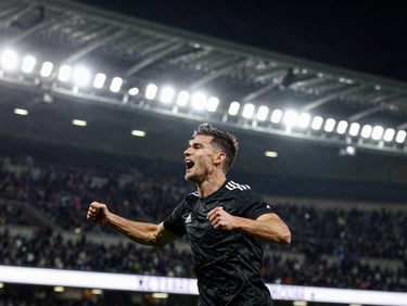 Sharp close-up of a football player celebrating a goal passionately, dynamic stadium lights, high contrast, 35mm