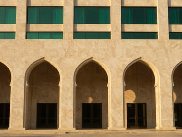 Warm golden-hour light hitting the symmetrical stone arches of a modern hotel facade in Madinah, clean architectural lines, 35mm photography